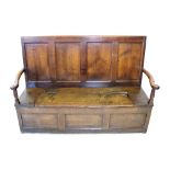 An early 18th century oak box-seat settle, the four panel high back flanked by curvilinear arms,