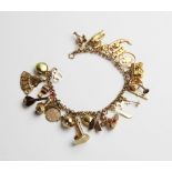 A yellow metal charm bracelet, the unmarked belcher link bracelet with applied beaded decoration,