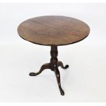 A George III oak tripod table, the circular four plank tilt top raised upon a cylindrical ring