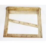 A rustic pine hanging wall rack, with a rectangular shelf above a pair of uprights united by an