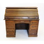 An early 20th century oak roll top desk, the 'S' shaped tambour front enclosing a