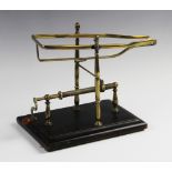A late 19th century wine decanting cradle, the frame formed from lacquered brass supported by turned