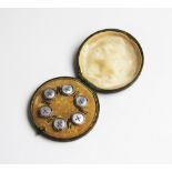 A cased set of six buttons, each designed as a circular mother of pearl panel with central wire X,