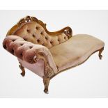 A Victorian walnut framed chaise longue, the shaped back with a carved crest extending to a leaf