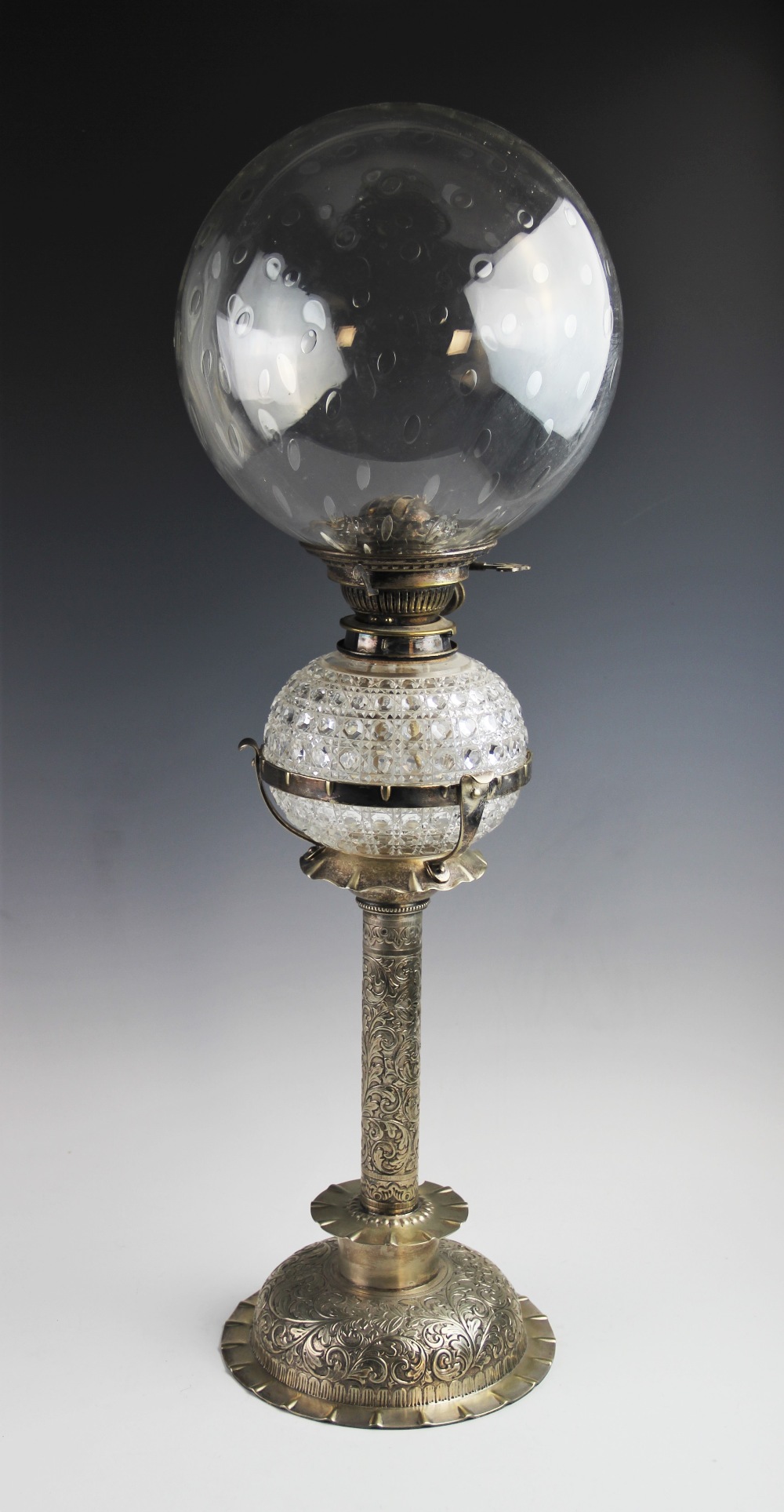 A late 19th century white metal oil lamp by Hinks & Sons, the bubble blown spherical glass shade