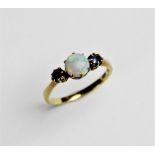An opal and sapphire 14ct three stone ring, the central round untested opal cabochon approx. 6mm