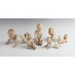 A set of three graduated Gebruder Heubach piano dolls, each modelled crawling on their front,