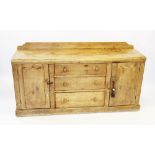 A Victorian pine kitchen dresser base, the rectangular top above a central inverted cupboard door,