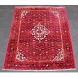 A Tabriz village wool carpet, the central lozenge shaped medallion on a vibrant red ground,