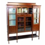 An Edwardian inlaid mahogany inverted breakfront display cabinet, the shaped pediment above a