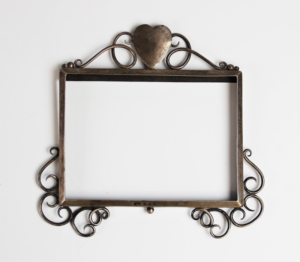 An Arts Crafts silver photograph frame, Birmingham 1897, the rectangular frame with heart shaped