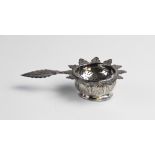 A middle eastern white metal tea strainer and stand, the strainer with with pierced circular bowl,