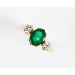An emerald and diamond 3-stone ring, the central oval mixed cut emerald (measuring 8.5mm x 6.5mm x