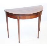 A George III demi-lune mahogany card table in the Sheraton manner, the rosewood cross banded top