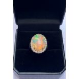 An opal and diamond cluster ring, the central oval natural opal cabochon (measuring 15.2mm x 11.