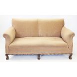 An early 20th century walnut and upholstered settee, covered in tan fabric, the padded scrolled arms