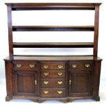A George III oak North Walian breakfront dresser, the open plate rack with a moulded cornice above
