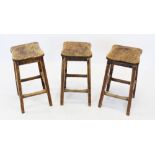 A trio of mid 20th century elm seated stools, the shaped and figured elm seats raised upon out set
