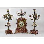 A late 19th century French rouge marble and gilt metal clock garniture, the clock with an urn finial