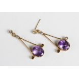 A pair of amethyst and diamond drop earrings, each comprising an oval mixed cut amethyst (