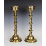 A pair of brass ecclesiastical candlesticks, each with a stiff leaf frieze upon a knopped column and