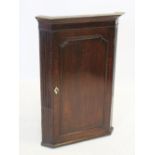 A George III oak straight front hanging corner cupboard, the moulded cornice above a single