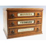 An early 20th oak three drawer haberdashery chest, advertising 'Morris and Yeomans Needles' in verre