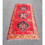A large heavy pile Iranian carpet, with an Aztec medallion design against a red ground, 320cm x