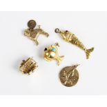 A selection of gold and yellow metal charms, to include a yellow metal articulated fish with red