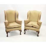 A pair of George II style wing back fireside armchairs, early 20th century, covered in embossed