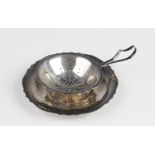 A silver tea strainer and drip bowl by Bishton's Ltd, Birmingham 1970, the bowl with pierced