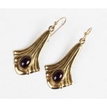A pair of Art Nouveau style garnet drop earrings, each comprising a polished oval garnet cabochon (