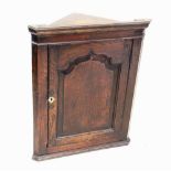 A George III oak hanging corner cupboard, with a fielded panelled straight front single door opening