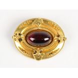 A Victorian Etruscan style memorial brooch, comprising a central garnet cabochon measuring 19mm x