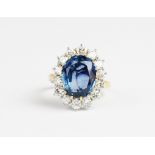 A sapphire and diamond cluster ring, the central untested oval mixed cut sapphire (measuring 12.54mm