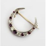 A diamond and ruby set crescent brooch, comprising eight graduated round brilliant cut diamonds