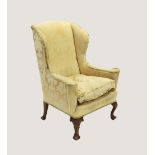 A George II style wing back fireside armchair, early 20th century, covered in classical foliate