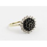 A diamond cluster ring, the central tiered cluster comprising nineteen round mixed cut black