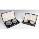 A cased pair of cut glass butter dishes, each 8.7cm wide, each with accompanying silver butter