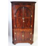 A George III mahogany free standing corner cupboard, the cavetto cornice above a pair of cupboard