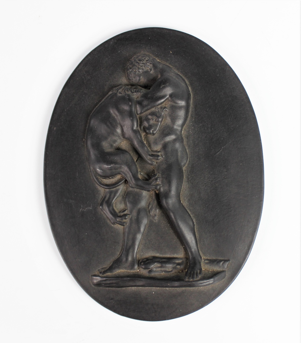 A Wedgwood black basalt oval plaque, 19th century, depicting Hercules strangling the Nemean Lion,