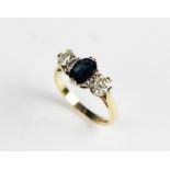 A diamond and sapphire three-stone ring, the central oval mixed cut sapphire measuring 7mm x 5mm,