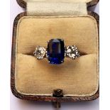 A sapphire and diamond three stone ring, the central cushion cut sapphire (9.2mm x 6.4mm x 5.9mm,