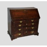 A George III oak and mahogany cross banded bureau, the moulded fall front enclosing an arcaded