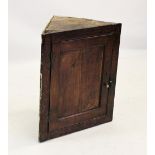 An 18th century oak straight front hanging corner cupboard, the single panelled door enclosing two