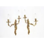 A pair of early 20th century French gilt metal two branch wall light fittings, each cast with