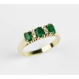 An emerald and diamond ring, comprising three mixed cut oval emeralds each measuring 4.7mm x 3mm,