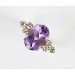 An amethyst and diamond ring, the central oval mixed cut amethyst (measuring 14mm x 10mm), with