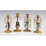 Four gilt metal lustre hung candlesticks, 19th century, each with three cast dark metal cherubs