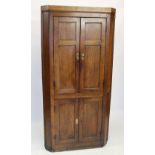 A George III oak free standing corner cupboard, the upper panelled doors opening to three shelves,